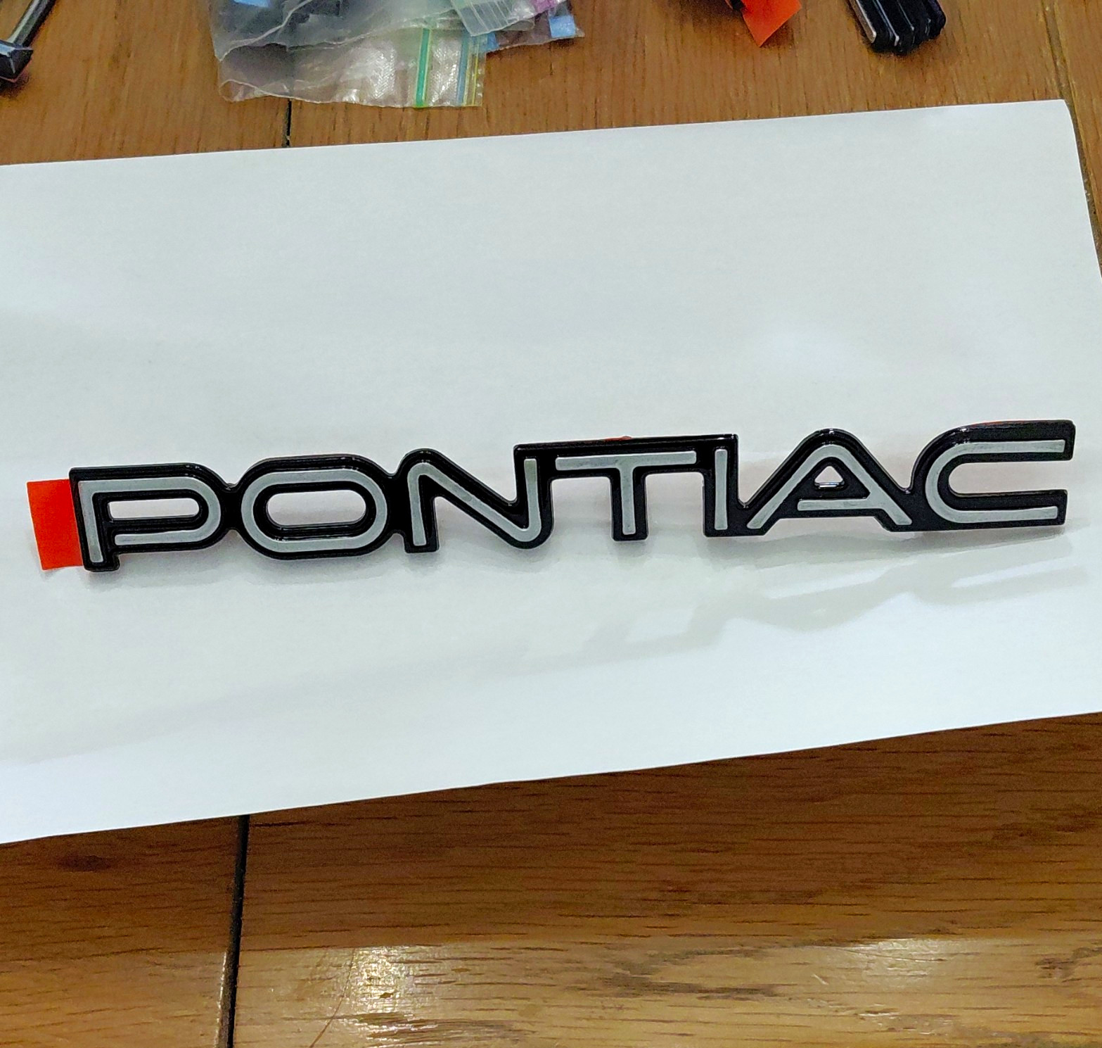 1984 - 1988 Pontiac Fiero Rear Fascia Emblem Silver Over Black NOS OEM GM Piece